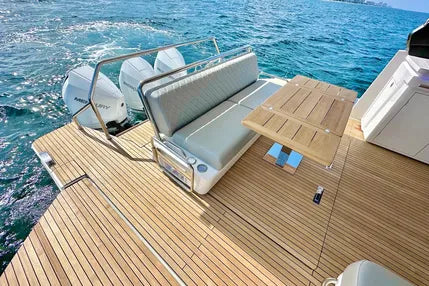 Yacht deck with wooden flooring, white cushioned bench, and table on a body of water at culebra island